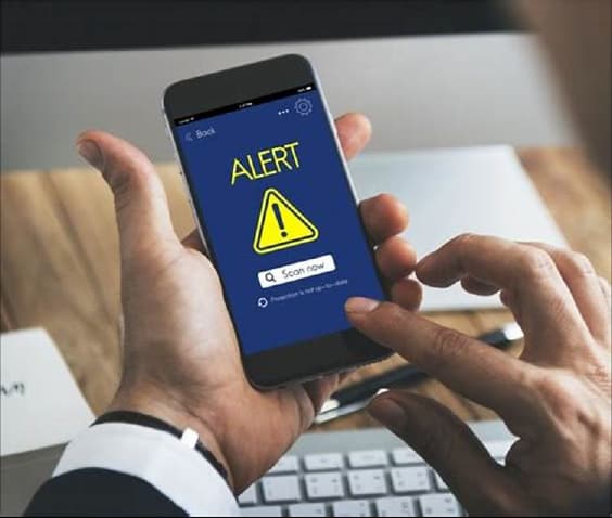 A smartphone screen showing a cautionary "Alert" notification, with a warning triangle and an option to scan now.
