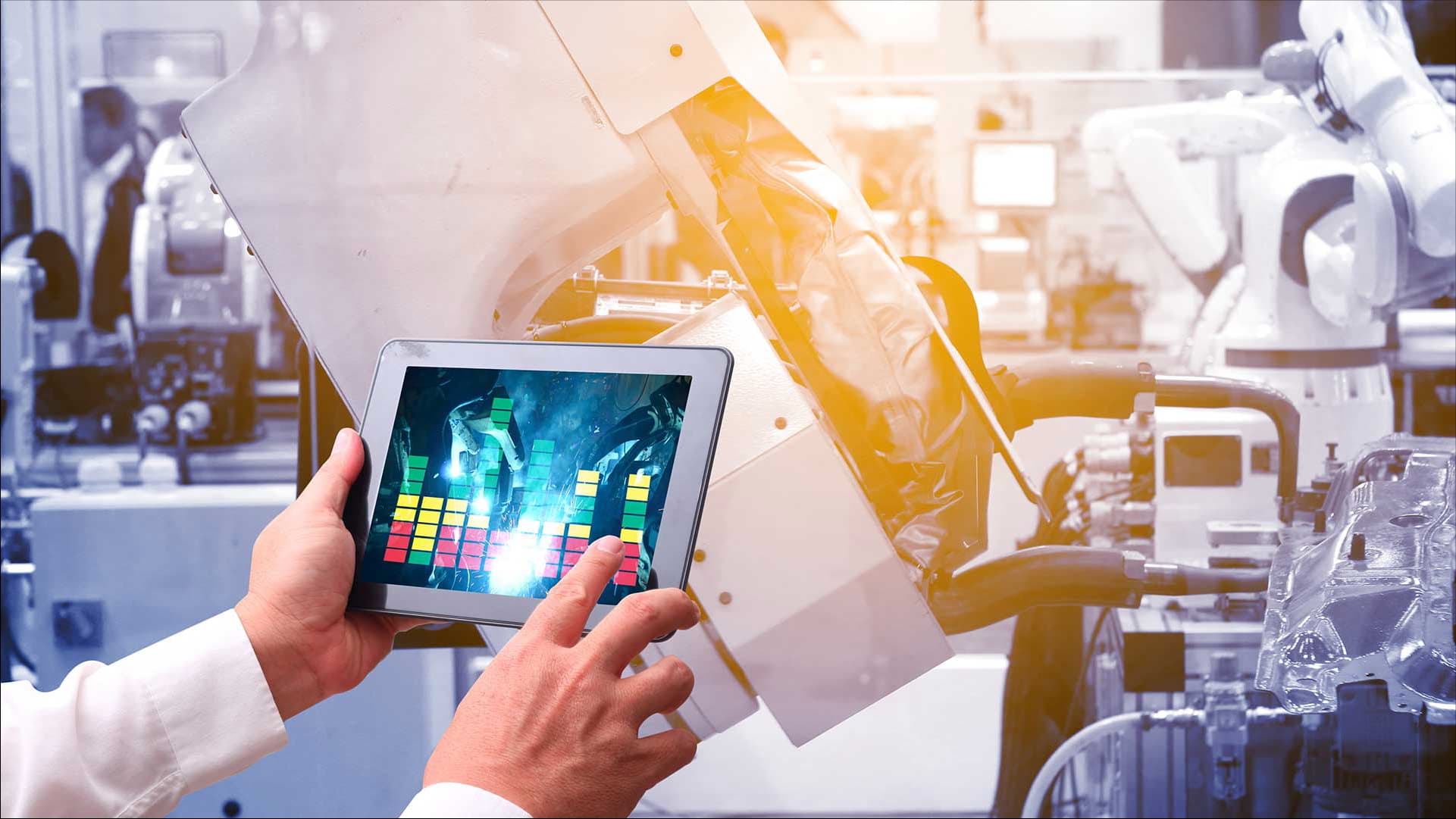 A person using a tablet to control robotic machinery in an industrial setting, emphasizing automation and IoT integration.