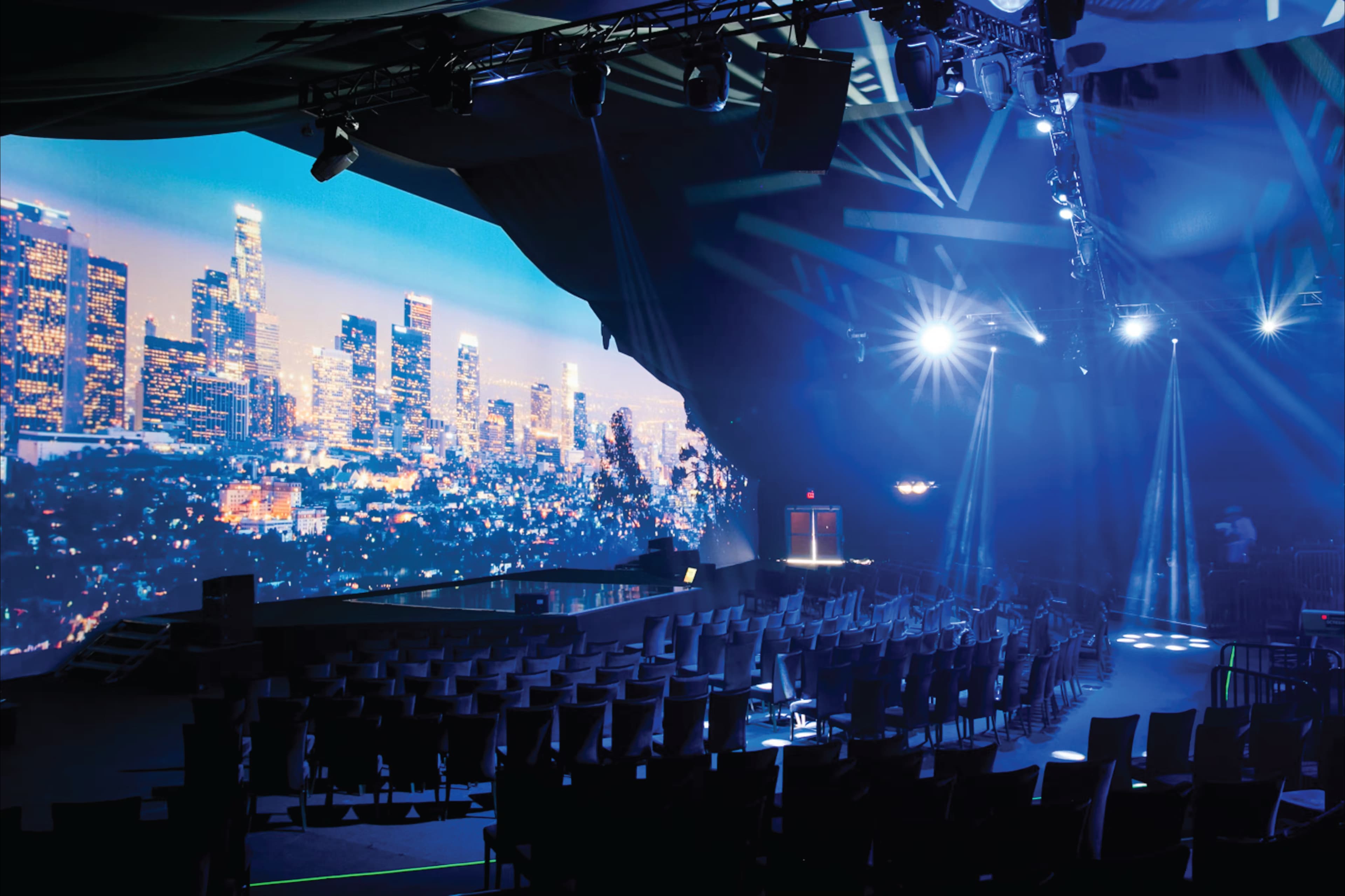 A large event setup with a digital cityscape displayed on a screen, showcasing immersive technology used for virtual events and live broadcasts in Meta Stadium.