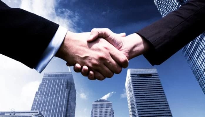 Handshake with skyscrapers in the background symbolizing trustworthy partnerships.