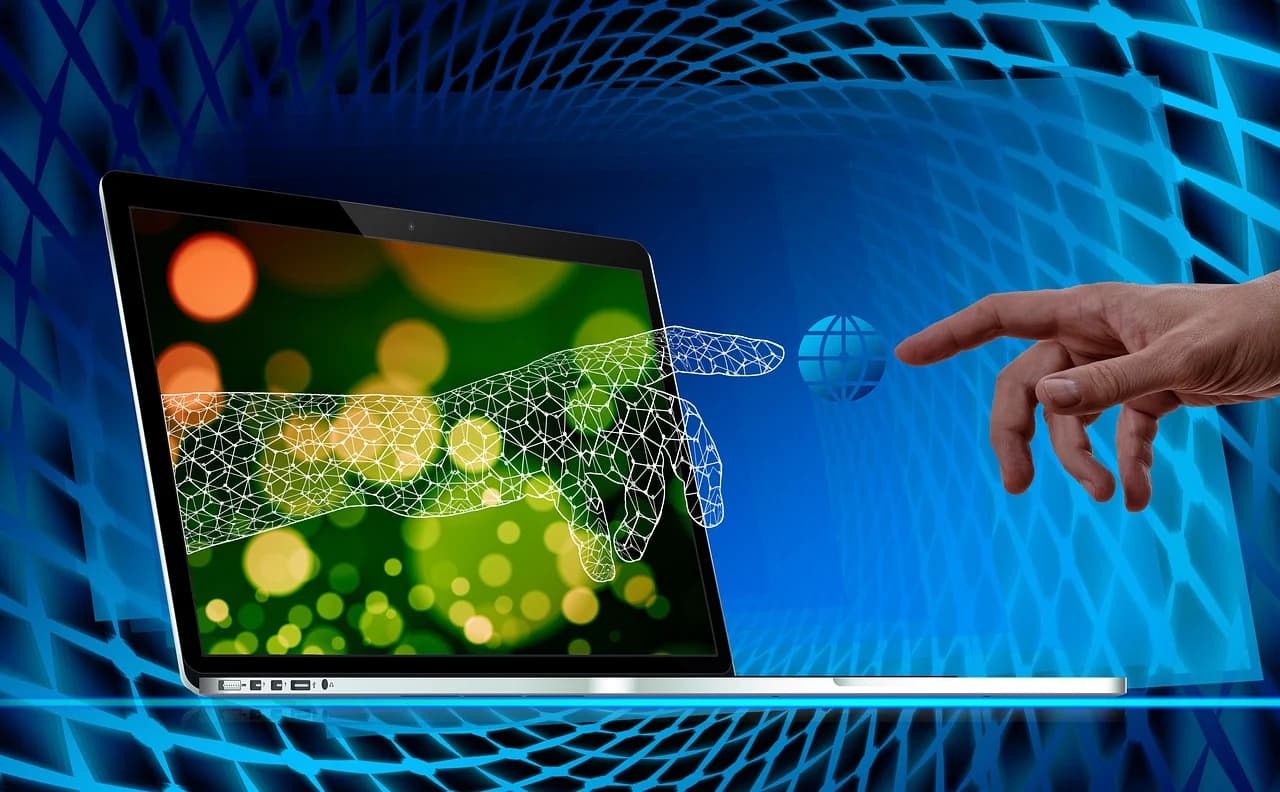 A hand and a digital mesh hand reaching out from a laptop screen, illustrating the integration of technology and human touch in collaboration.