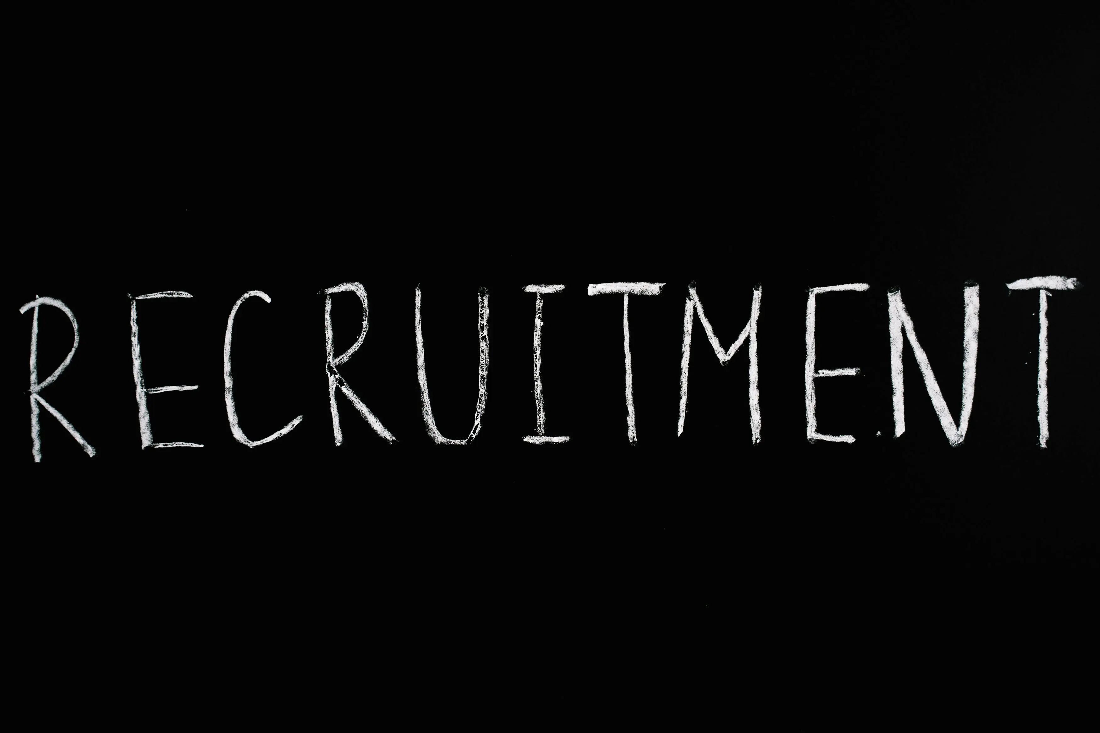 The word RECRUITMENT written in bold, chalk-style lettering on a blackboard background, emphasizing the focus on talent acquisition.