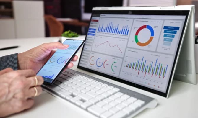 A desktop screen and smartphone showing detailed analytics dashboards with colorful graphs and charts.