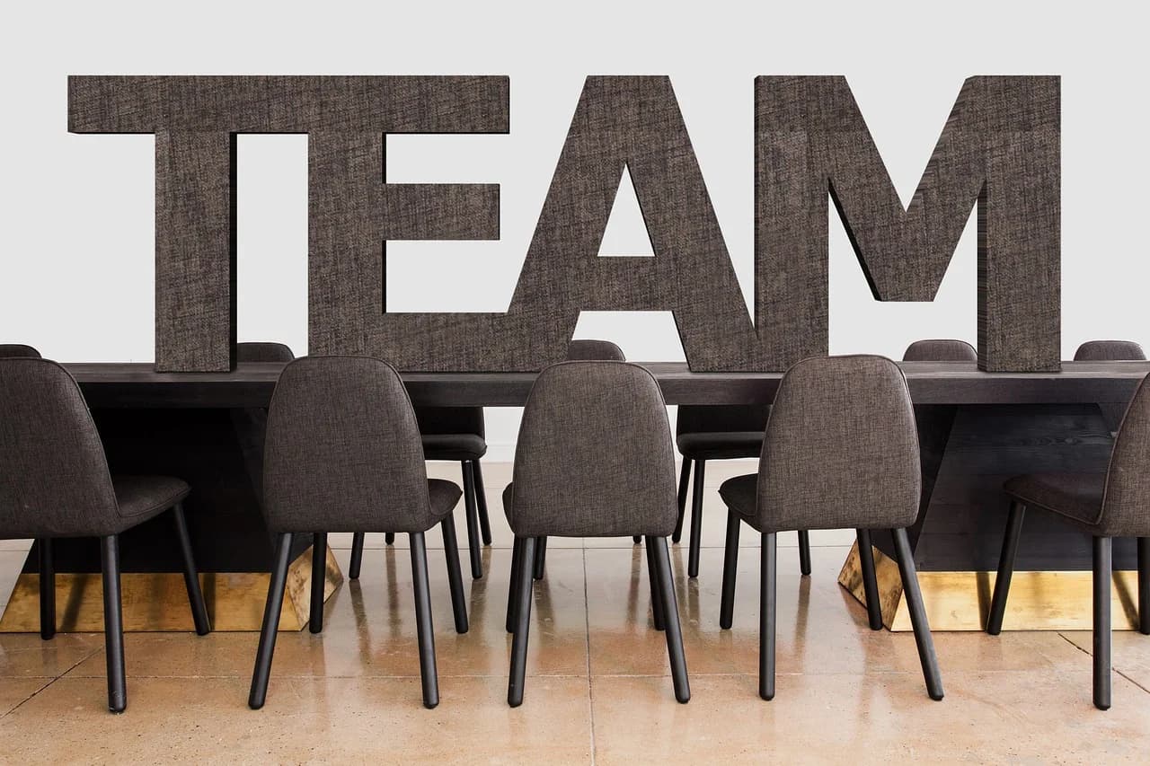 A modern conference table with large block letters spelling "TEAM," representing collaboration and unity in a professional setting.